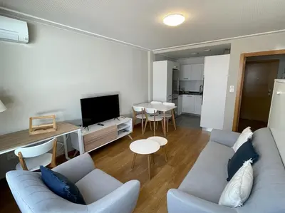 a living room with a blue couch and a kitchen at Estudio céntrico 2 con terraza y parking privado in Ourense