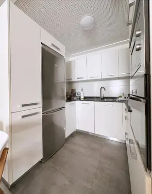 a kitchen with white cabinets and a stainless steel refrigerator at Estudio céntrico 2 con terraza y parking privado in Ourense