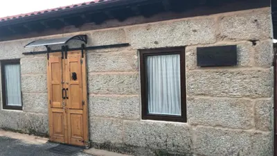 a stone building with a wooden door and two windows at Casa Escuela Trasmiras, Casa dos Mestres in Trasmiras