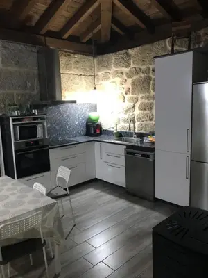 a kitchen with white appliances and a table and a table and chairs at Casa Escuela Trasmiras, Casa dos Mestres in Trasmiras