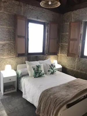 a bedroom with a large bed with two night stands at Casa Escuela Trasmiras, Casa dos Mestres in Trasmiras