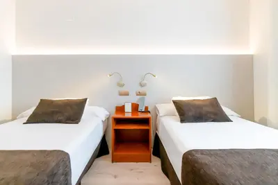 two beds in a room with a table between them at Ponferrada Plaza in Ponferrada