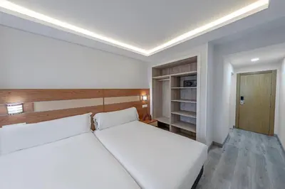 a bedroom with a white bed and a closet at Hotel Faranda Los Tilos, Ascend Hotel Collection in Teo