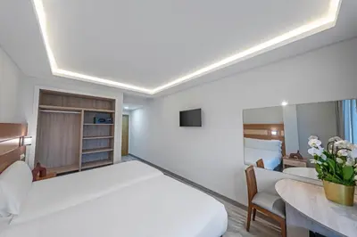a bedroom with a large white bed and a desk at Hotel Faranda Los Tilos, Ascend Hotel Collection in Teo