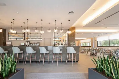 a restaurant with a bar with white stools at Aparthotel Attica21 As Galeras in Bastiagueiro