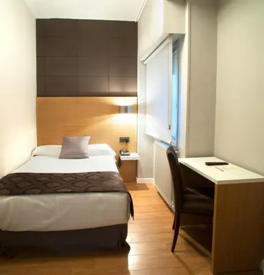 a bedroom with a bed and a desk and a bed and a chair at Hotel Universal in Santiago de Compostela