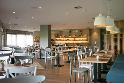 a restaurant with wooden tables and white chairs at Hotel Santiago Apóstol in Santiago de Compostela