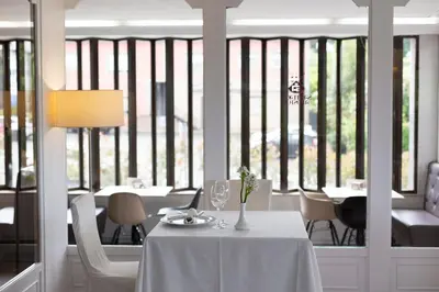 a dining room with a white table and chairs and windows at Hotel Santiago Apóstol in Santiago de Compostela