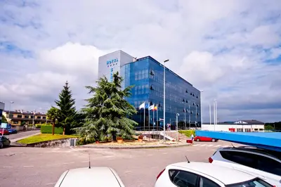 a large glass building with cars parked in a parking lot at Hotel Auditorio Santiago & Spa in Lugo