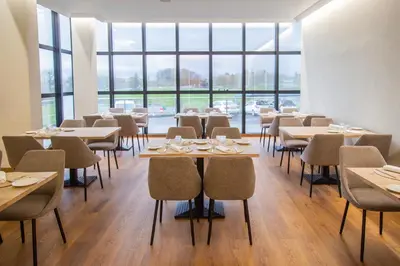 a dining room with tables and chairs and windows at Hotel Auditorio Santiago & Spa in Lugo