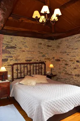 a bedroom with a bed and a stone wall at Casa Assumpta in Arzúa
