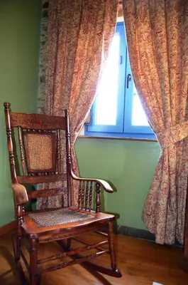 a wooden rocking chair sitting in front of a window at Casa Assumpta in Arzúa