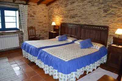 a bedroom with a large bed with blue pillows at Casa Assumpta in Arzúa