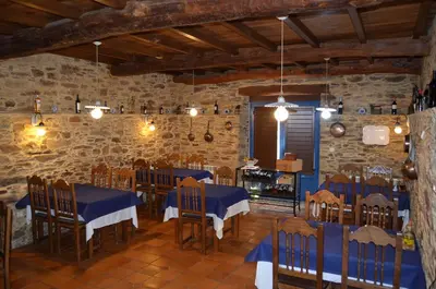 a restaurant with blue tables and chairs in a stone wall at Casa Assumpta in Arzúa