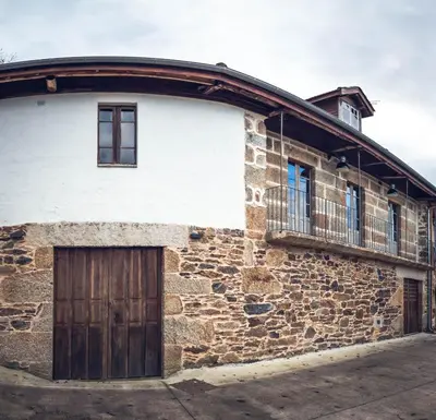 an old stone building with a wooden door and a balcony at Houmi As Bouzas in Castrelo de Miño