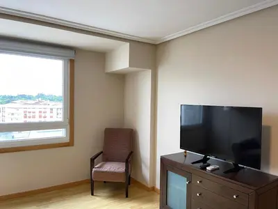 a living room with a flat screen tv and a chair at Aparthotel Arenteiro in Carballino