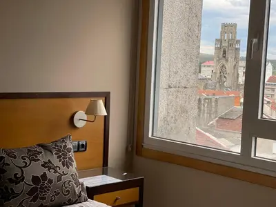 a bedroom with a bed and a large window at Aparthotel Arenteiro in Carballino