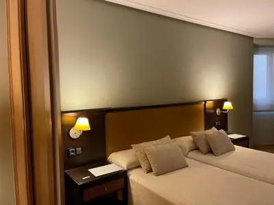 a hotel room with a bed and two lamps at Aparthotel Arenteiro in Carballino
