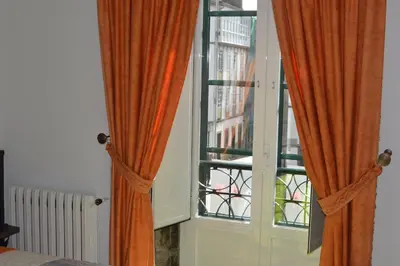 an open window with orange curtains in a bedroom at Pensión Da Estrela in Santiago de Compostela