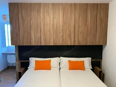 a bed with two orange pillows on top of it at Pensión Da Estrela in Santiago de Compostela
