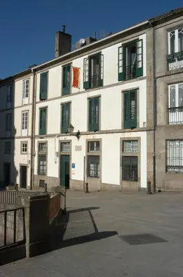 a large white building with green shuttered windows at Pensión Da Estrela in Santiago de Compostela