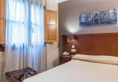 a bedroom with a bed with a wooden headboard and a telephone at Hotel Herradura in Santiago de Compostela