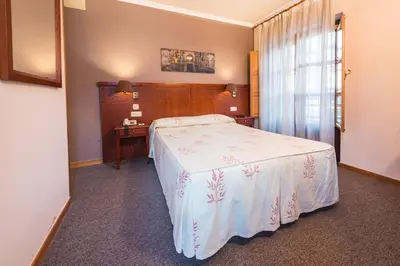 a bedroom with a bed and a desk and a window at Hotel Herradura in Santiago de Compostela