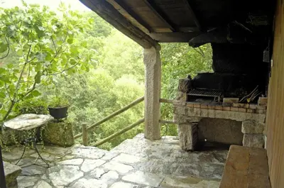 a porch with a stone fireplace in a forest at Casa da Laxa in Beáriz