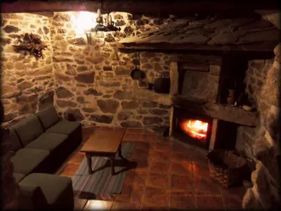 a living room with a fireplace in a stone building at Casa da Laxa in Beáriz