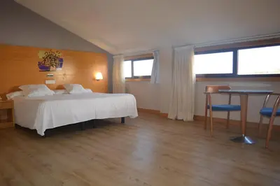 a bedroom with a white bed and a table and a desk at Ruta Jacobea in Lavacolla
