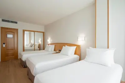 two beds in a hotel room with white sheets at Exe Area Central in Santiago de Compostela