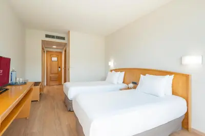 a hotel room with two beds and a desk at Exe Area Central in Santiago de Compostela