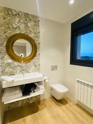 a bathroom with a sink and a toilet and a mirror at El Pueblín del Pinar in Navia
