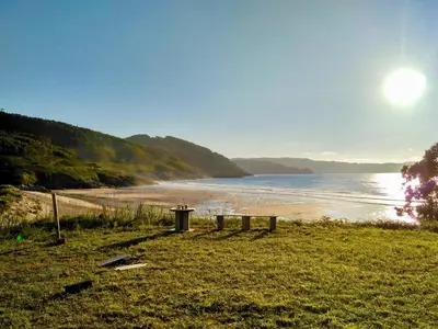 a beach with a trash can next to the water at The Cliffs - Passion Eccehomo in Viveiro