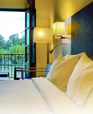 a bedroom with a bed with two lamps and a window at Eurostars Vila de Allariz Hotel Balneario in Allariz