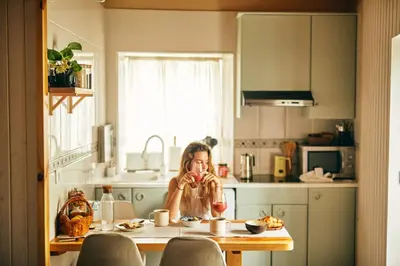a woman sitting at a table in a kitchen at Casa Montse. Apartamentos turísticos in Ribadeo