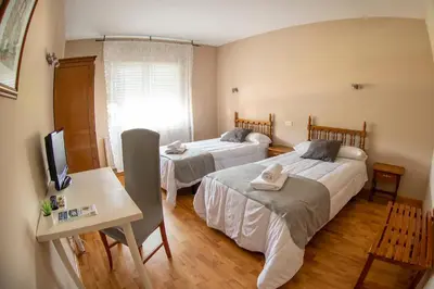 a room with two beds and a table and a television at Hotel Voar in Ribadeo