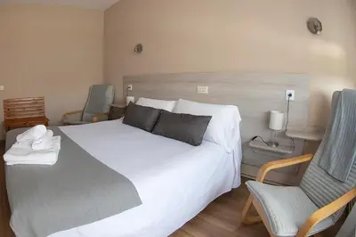 a bedroom with a large white bed and a chair at Hotel Voar in Ribadeo