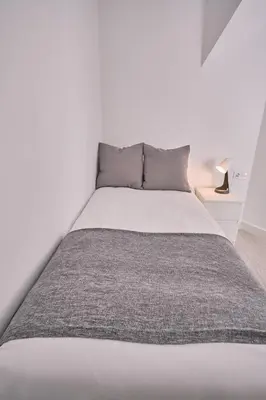 a bedroom with a large bed with a gray blanket at Dadá Coliving & Rooms by Serendipia Turismo in Santiago de Compostela