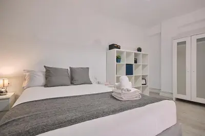 a white bedroom with a large bed and a white shelf at Dadá Coliving & Rooms by Serendipia Turismo in Santiago de Compostela