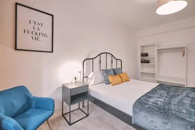 a bedroom with a bed and a blue chair at Dadá Coliving & Rooms by Serendipia Turismo in Santiago de Compostela