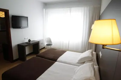 a bedroom with a bed with a lamp and a window at Hotel Mendez Nuñez in Lugo