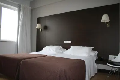 a hotel room with two beds and a window at Hotel Mendez Nuñez in Lugo