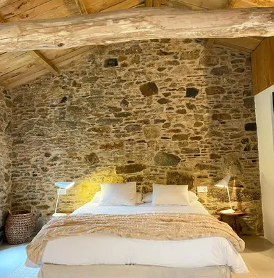 a bedroom with a stone wall with a bed at Lar do Gado in Porta