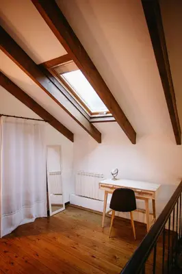 an attic room with a table and a skylight at Apartamentos Rurales La Casina del Fontan in Valle de Lago