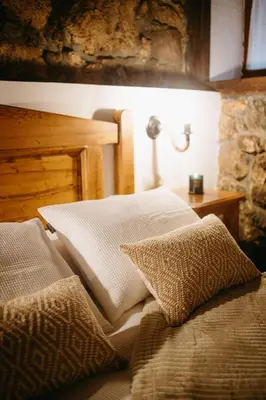 a bed with two pillows and a table with a lamp at Apartamentos Rurales La Casina del Fontan in Valle de Lago