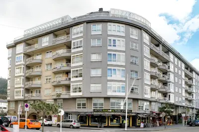a large building with cars parked in front of it at Duerming Park Viveiro in Viveiro