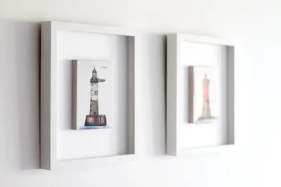 three framed pictures of lighthouses on a wall at Duerming Park Viveiro in Viveiro
