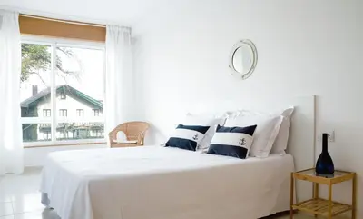 a white bedroom with a bed with blue and white pillows at Duerming Park Viveiro in Viveiro