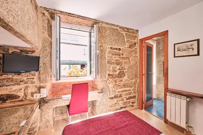 a room with a red chair and a window at Hotel Entrecercas in Santiago de Compostela